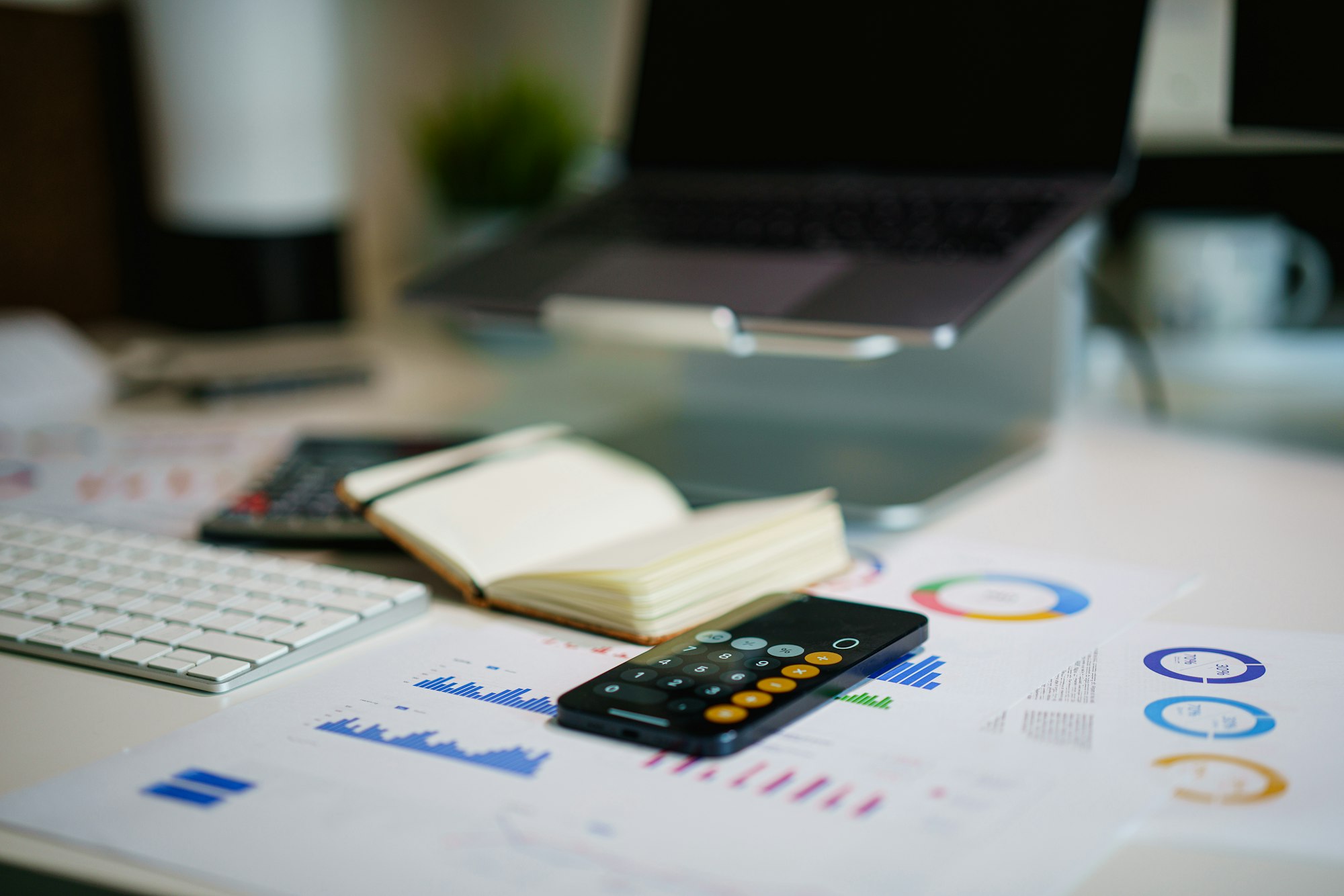 A desk with financial charts on a screen and a smartphone